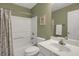 Well-lit bathroom featuring a shower-tub combination, white cabinets, and olive green walls at 2145 Charleston Oak Cir, Lawrenceville, GA 30043