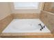 The primary bath has a large soaking tub surrounded by travertine tile at 516 Black Horse Cir, Canton, GA 30114
