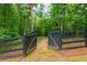 Gated fence opening to an expansive yard surrounded by mature trees, providing privacy and a natural setting at 516 Black Horse Cir, Canton, GA 30114