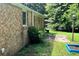 Side view of the brick house, featuring a concrete patio and greenery at 6521 Menlo Way, Rex, GA 30273