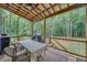 Covered back porch with a dining table and grill, perfect for outdoor entertaining with a view of the wooded backyard at 104 Woodland Ln, Canton, GA 30114