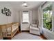 Cozy Bedroom featuring neutral tones, wood floors, a wooden crib, and a comfortable chair at 1360 Edmund Ne Ct, Atlanta, GA 30306