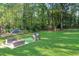 Large backyard with patio seating, playhouse, and ample green space surrounded by trees at 151 Quail Hollow Dr, Dallas, GA 30157