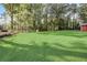 A large backyard with lush lawn, mature trees, play equipment, and shed, providing ample space for outdoor activities at 151 Quail Hollow Dr, Dallas, GA 30157