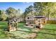 Backyard with a custom play area, patio seating, a large, well-maintained lawn, and mature trees at 151 Quail Hollow Dr, Dallas, GA 30157