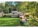 Expansive backyard featuring a wooden deck, patio with seating, playhouse, and a well-maintained lawn surrounded by trees at 151 Quail Hollow Dr, Dallas, GA 30157