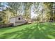 Green backyard with a well-maintained lawn, mature trees, play equipment, and patio area with seating at 151 Quail Hollow Dr, Dallas, GA 30157