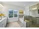 Bright bathroom features a glass shower, soaking tub, tile flooring, double sink vanity, and natural light at 1637 Short Shadow Ln, Snellville, GA 30078