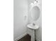 Modern bathroom features a pedestal sink, oval mirror, and silver light fixture against a white wall at 1637 Short Shadow Ln, Snellville, GA 30078