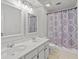 Clean bathroom featuring double sinks, vanity and tiled shower with patterned curtain at 200 Creek Run Ct, Alpharetta, GA 30005
