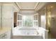 Bright bathroom features a soaking tub with jets under a window with plantation shutters and separate glass-enclosed shower at 3071 Intrepid Wake, Marietta, GA 30062