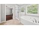 Bathroom featuring a large soaking tub, glass shower and a window for natural light at 1220 Roswell Manor Cir, Roswell, GA 30076