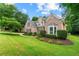 Beautifully landscaped front yard of a brick home with a curved driveway, mature trees, and green lawn at 1995 Settindown Dr, Roswell, GA 30075
