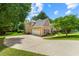 Side view of a brick and tan home with a two-car garage and wide driveway surrounded by green lawn at 1995 Settindown Dr, Roswell, GA 30075