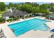 Community swimming pool featuring multiple lounge chairs and patrons enjoying a swim on a summer day at 1995 Settindown Dr, Roswell, GA 30075