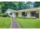 Lovely white home featuring a manicured lawn, stone walkway, and a covered entryway surrounded by lush greenery at 2440 Weatherford Ct, Marietta, GA 30068