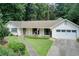 Inviting single-story home boasts fresh white paint, a lush lawn, and mature trees, complete with an attached garage at 2440 Weatherford Ct, Marietta, GA 30068