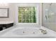Close-up of a garden tub with jacuzzi jets and a view to the backyard through a window at 77 Skyland Dr, Roswell, GA 30075