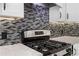 Close-up of kitchen range featuring mosaic backsplash, granite countertops, and sleek appliances at 77 Skyland Dr, Roswell, GA 30075