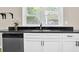 Bright kitchen features white cabinets, black countertops, stainless steel dishwasher, and a window overlooking greenery at 91 Tatum St, Marietta, GA 30060