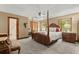 A bedroom boasts a four-poster bed, neutral carpet and walls, and bright natural light at 3500 Thunderwood Ln, Snellville, GA 30039