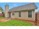 A backyard view of a cozy home featuring a well-maintained lawn and a neutral-toned exterior with bright, window-lit rooms at 420 Spring Lake Ter, Covington, GA 30016
