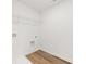 White laundry room with wooden floors and a metal shelf for storage at 2472 Cotton Ln, Douglasville, GA 30135