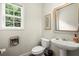 Quaint powder room featuring a pedestal sink, decorative mirror and artwork, and a window for natural light at 3070 Jardin Nw Ln, Kennesaw, GA 30152