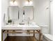 The modern bathroom has double sinks with gold hardware and lighting and a tiled walk-in shower at 2244 Alpha Dr, Decatur, GA 30032