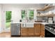 Charming kitchen featuring floating shelves, stainless steel dishwasher, and a farmhouse sink at 2244 Alpha Dr, Decatur, GA 30032