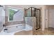Modern bathroom showcasing a soaking tub, glass-enclosed shower, and neutral tile at 2307 Loughridge Dr, Buford, GA 30519