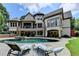 Beautiful backyard featuring a pool, hot tub, multiple patios, lush landscaping, and a spacious home exterior at 2910 Creek Tree Ln, Cumming, GA 30041