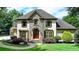 Charming two-story home with a stone facade, arched entryway, lush landscaping, and a well-maintained lawn at 2910 Creek Tree Ln, Cumming, GA 30041
