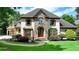 Elegant home featuring a manicured lawn, stone accents, and a welcoming arched entryway with a wood door at 2910 Creek Tree Ln, Cumming, GA 30041