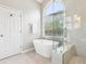 Bright bathroom featuring a soaking tub, glass enclosed shower, and a large arched window at 3405 Glenrose Trail Trl, Atlanta, GA 30341