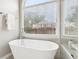 Bright bathroom with a modern tub, walk-in shower, and window overlooking the backyard at 3405 Glenrose Trail Trl, Atlanta, GA 30341