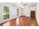 Bright living room with gleaming wood floors, ceiling fan, and large windows showing a treed front yard at 240 Wellington Dr, Mcdonough, GA 30252