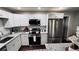 Modern kitchen features granite countertops, stainless steel appliances, white cabinetry, and backsplash with hardwood floors at 2443 Abner Nw Pl, Atlanta, GA 30318