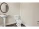 Elegant bathroom featuring a pedestal sink, oval mirror, and modern toilet on dark wood floors at 1630 Eaglerock Dr, Suwanee, GA 30024