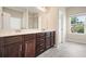 Bathroom featuring double sinks, dark wood cabinets, and a bright window at 1630 Eaglerock Dr, Suwanee, GA 30024