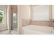 Modern bathroom featuring a walk-in shower and soaking tub beneath a large window at 1630 Eaglerock Dr, Suwanee, GA 30024
