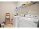 Bright laundry room with modern washer and dryer units and overhead shelving at 1630 Eaglerock Dr, Suwanee, GA 30024