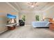 Bright bedroom with tray ceiling, ceiling fan, carpeting, large windows, and a TV on a wooden stand at 1630 Eaglerock Dr, Suwanee, GA 30024