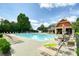 Community pool with lounge chairs, tables, umbrellas, and a red clubhouse set against a clear blue sky at 1630 Eaglerock Dr, Suwanee, GA 30024