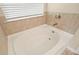 Modern white soaking tub with chrome fixtures and a large window at 1630 Eaglerock Dr, Suwanee, GA 30024
