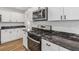 Modern kitchen with stainless steel stove and microwave, gray marble countertops and white cabinets at 2049 Phillips Dr, Atlanta, GA 30315
