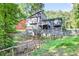 Backyard view of a two story home with a wooden deck and a small stream on a sunny day at 3328 Hidden Bluff Trl, Snellville, GA 30039