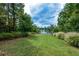 Scenic backyard view featuring a lush lawn that extends to a serene lake, framed by beautiful trees and landscaping at 505 Appalachian Woods Dr, Canton, GA 30114