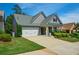 View of the well-maintained home featuring a two-car garage, a lush front yard, and stone accents at 505 Appalachian Woods Dr, Canton, GA 30114