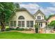 Rear view of home highlighting large windows, a charming patio area, and lush landscaping at 1000 Collingtree Ct, Mcdonough, GA 30253
